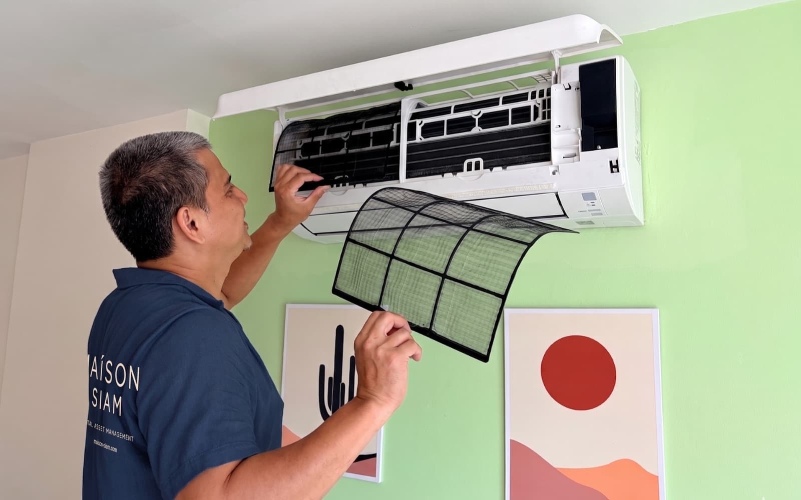 A Maison Siam technician servicing the air-conditioning in a managed unit